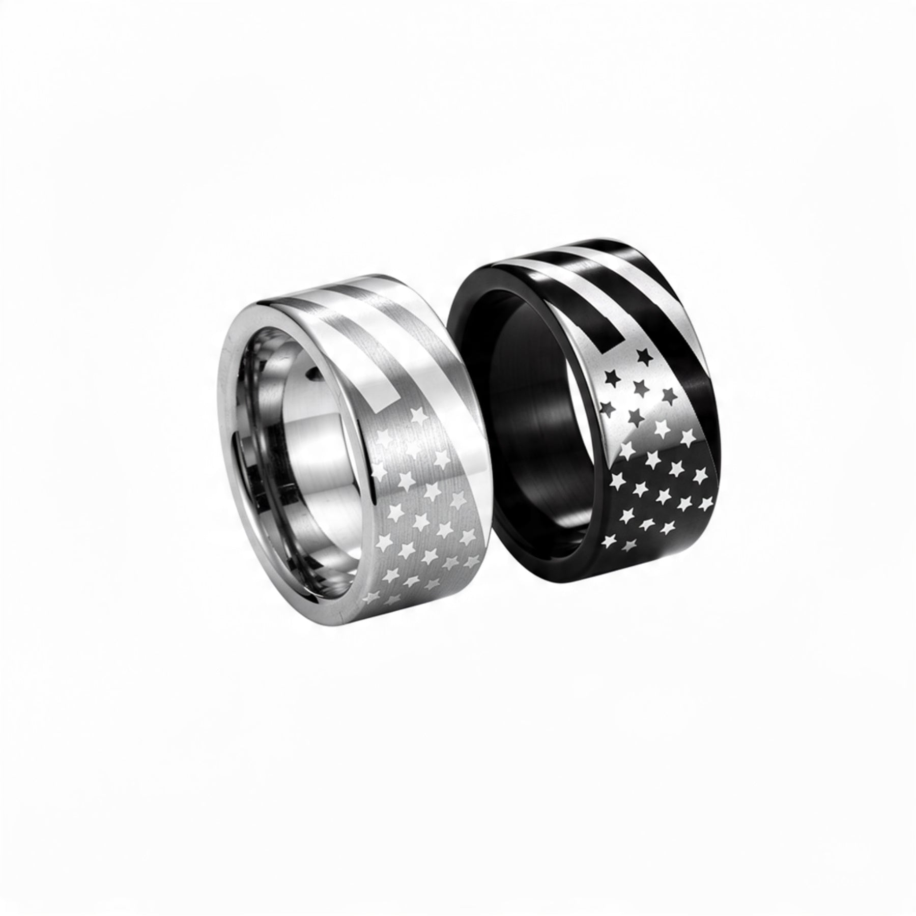 Two American flag stainless steel rings on pure white background, one brushed silver with engraved stars and stripes and one black band with white flag design