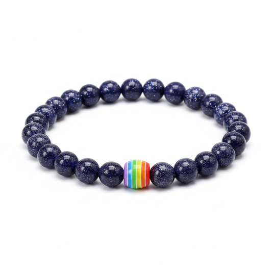 Deep blue shimmering sandstone bead bracelet with a central rainbow striped focal bead on a clean white background.
