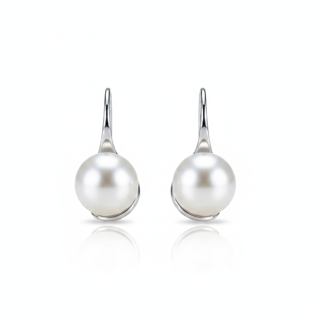 A high-resolution product shot of a pair of elegant pearl drop earrings featuring large, lustrous white pearls suspended from sleek silver-toned hooks, displayed against a pure white background with a soft reflection.