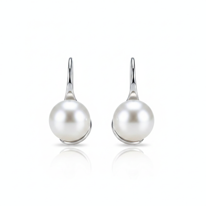 A high-resolution product shot of a pair of elegant pearl drop earrings featuring large, lustrous white pearls suspended from sleek silver-toned hooks, displayed against a pure white background with a soft reflection.