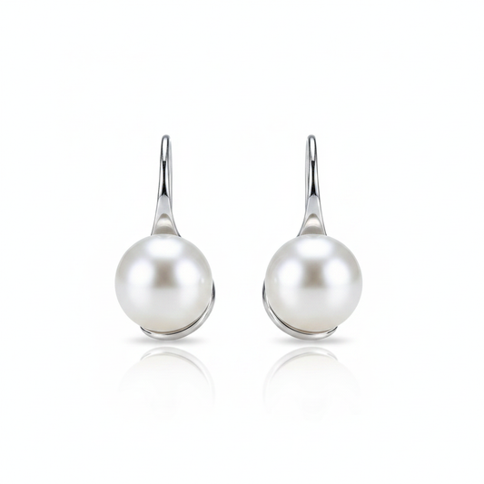 A high-resolution product shot of a pair of elegant pearl drop earrings featuring large, lustrous white pearls suspended from sleek silver-toned hooks, displayed against a pure white background with a soft reflection.