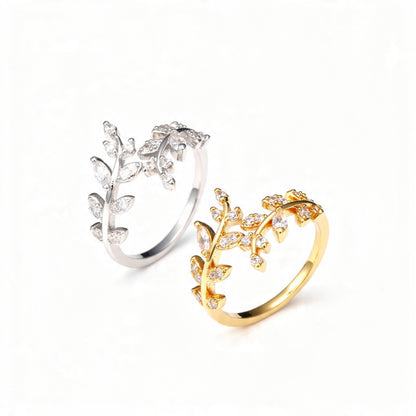 Two adjustable open rings designed as delicate branches with marquise and round crystals, shown in polished gold and silver finishes, centered on a pure white background.