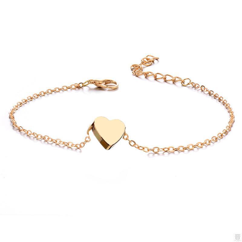 Minimalist gold-tone link chain bracelet featuring a solid polished heart charm, centered on a white background with an adjustable lobster clasp.