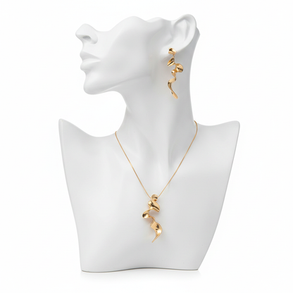 A luxury gold-toned jewelry set featuring a sculptural wavy pendant and matching spiral drop earrings on a minimalist white mannequin bust.