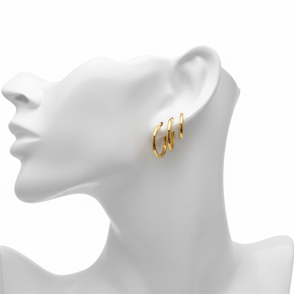 Set of three graduated gold-tone huggie hoop earrings with a high-polished finish, styled on a white mannequin profile to showcase a triple-pierced look.
