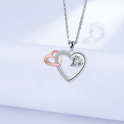 Elegant silver and rose gold interlocking heart pendant necklace with a brilliant heart-shaped crystal center stone.