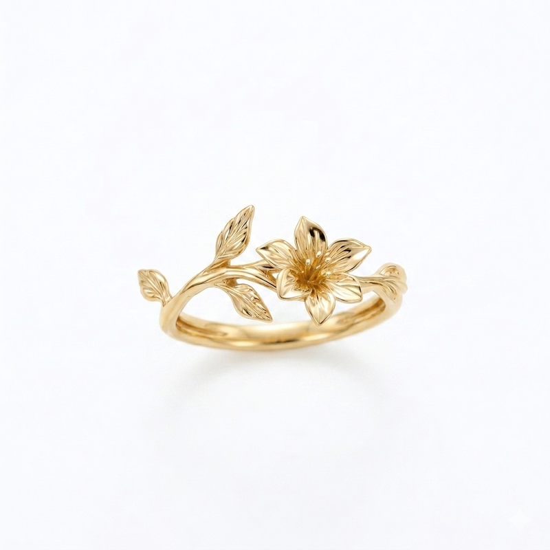 A delicate yellow gold ring with a single sculpted lily flower and an organic vine of leaves, set against a seamless white background.