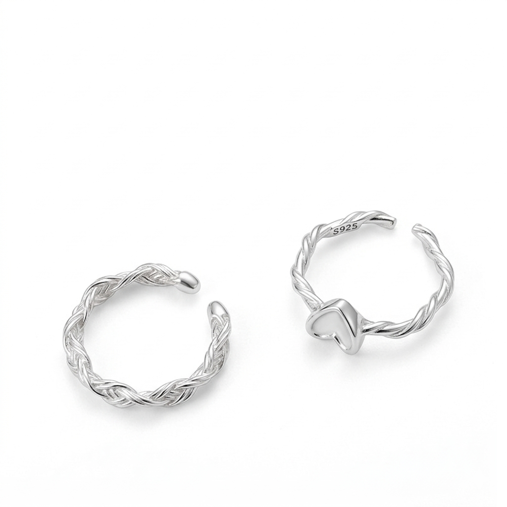 Two sterling silver adjustable rings, one braided-style band and one heart-motif twisted-band, on a pure white background.