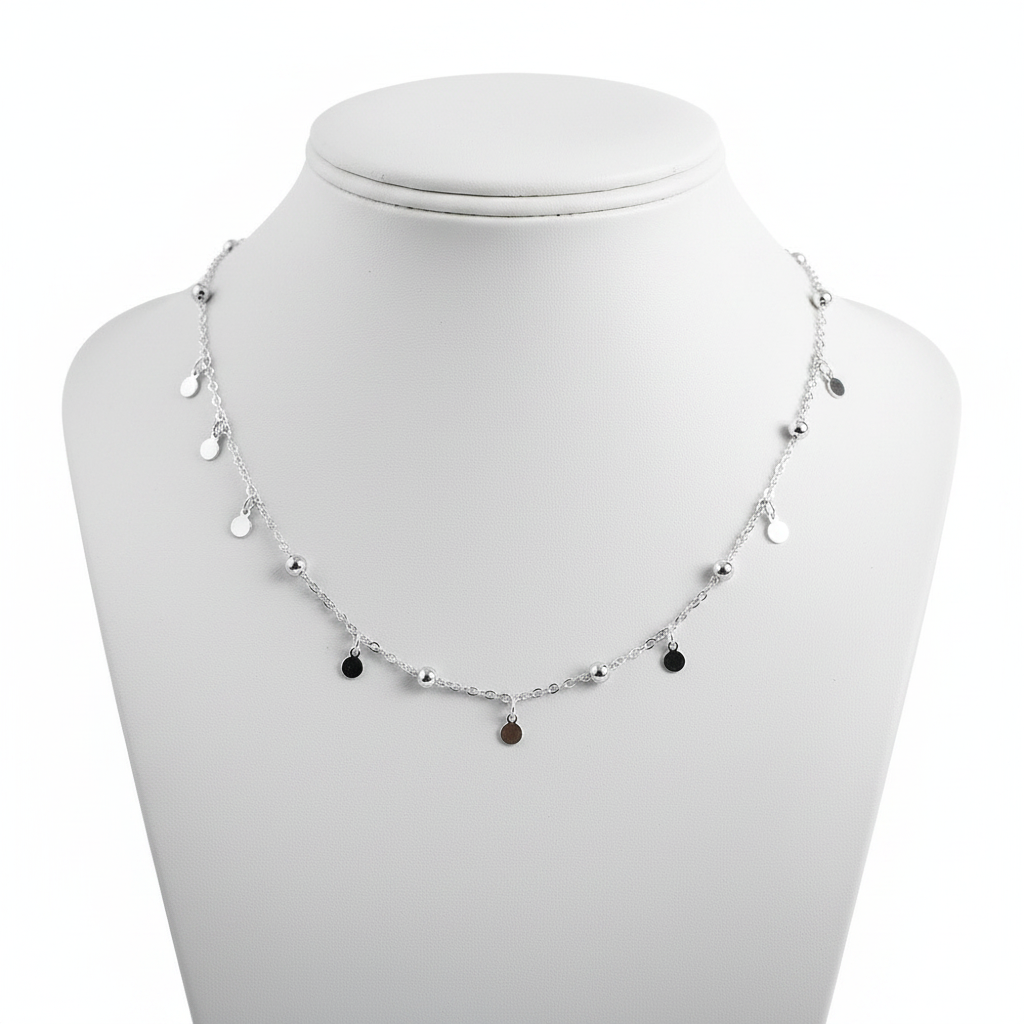 A high-resolution, close-up shot of a delicate sterling silver choker necklace featuring a thin link chain adorned with small polished silver beads and hanging circular disc charms, displayed on a clean white jewelry mannequin against a pure white background.
