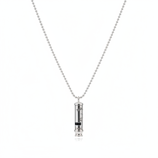 A high-shine, cylindrical silver-tone whistle pendant with engraved detailing, suspended from a classic ball chain necklace and shown against a clean white background.