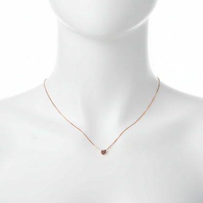A close-up, high-resolution shot of a dainty rose gold necklace featuring a tiny, polished heart pendant on a thin box chain, displayed on a clean white jewelry mannequin against a pure white background.