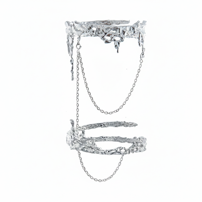 An avant-garde silver-toned double finger ring featuring a molten liquid-metal texture and delicate connecting chains, isolated on a white background.