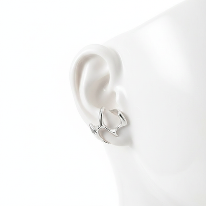 A minimalist silver-toned ear cuff with an organic molten metal design, displayed on a white mannequin ear to show its unique wrap-around fit.
