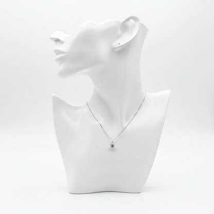 A delicate silver-toned necklace featuring a small sunflower-shaped pendant with a dark center, displayed on a minimalist white mannequin bust.