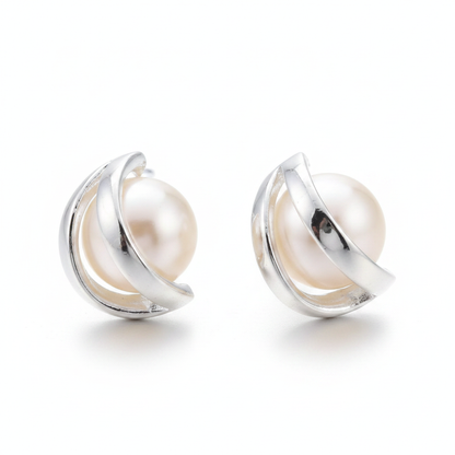 Pair of silver-tone stud earrings featuring a large cream-colored round pearl cradled in a modern, open-circle orbital frame on a clean white background.