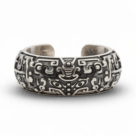 Antique oxidized silver open cuff ring with intricate taotie tribal carvings on pure white background, detailed mythological motif with blackened recesses, adjustable statement band