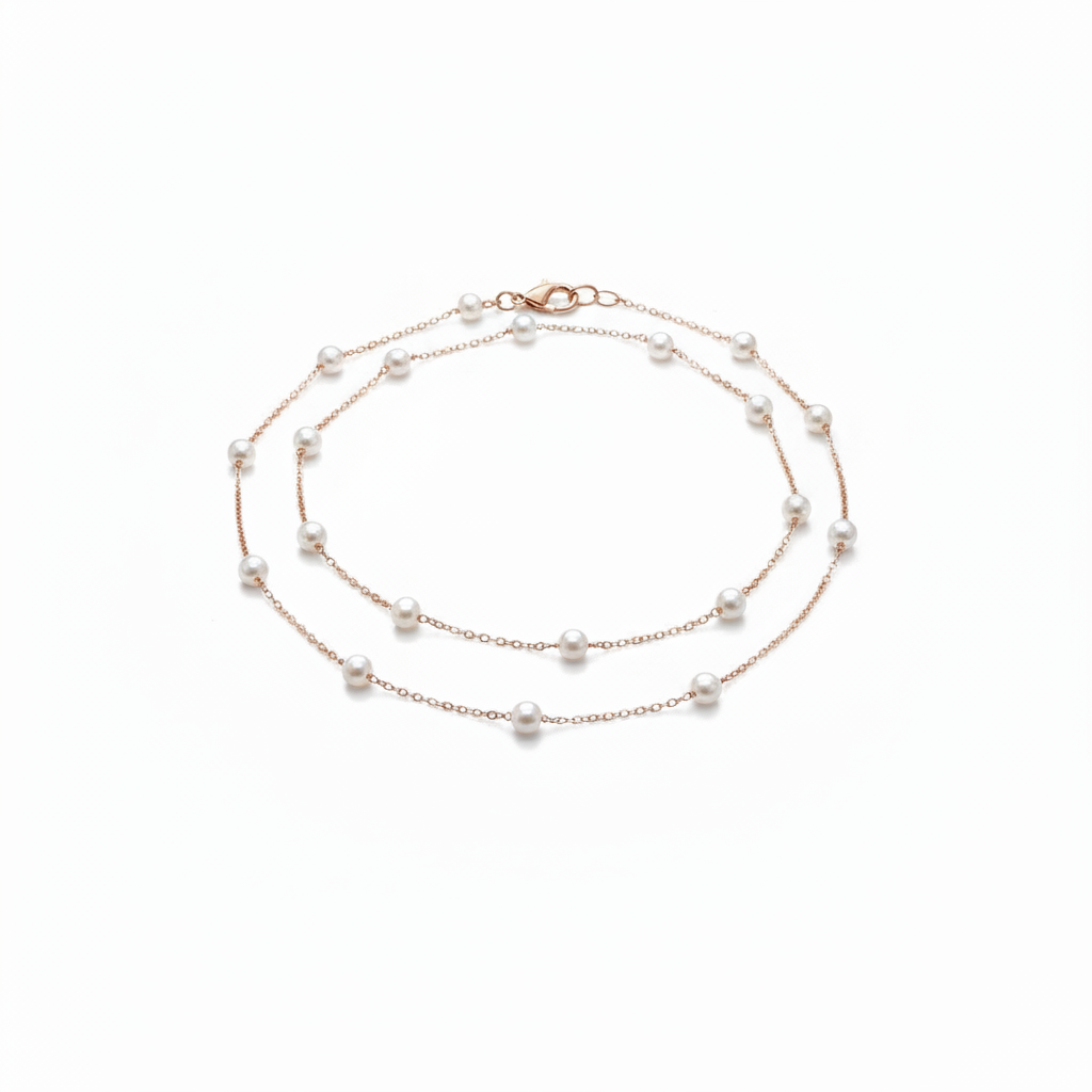 A delicate 18k gold-dipped double-layer anklet featuring evenly spaced "floating" pearls on a fine titanium steel chain, captured in a minimalist editorial style for a refined summer aesthetic.