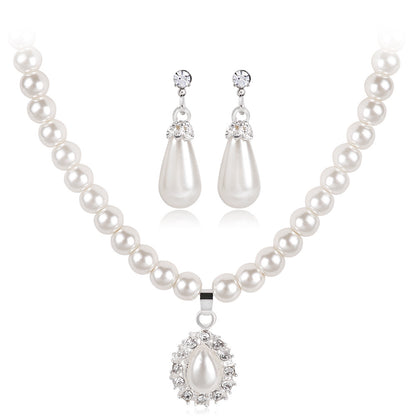 A sophisticated jewelry set featuring a classic pearl strand necklace with a crystal-encrusted teardrop pendant and matching drop earrings, reflecting a timeless and elegant editorial style.