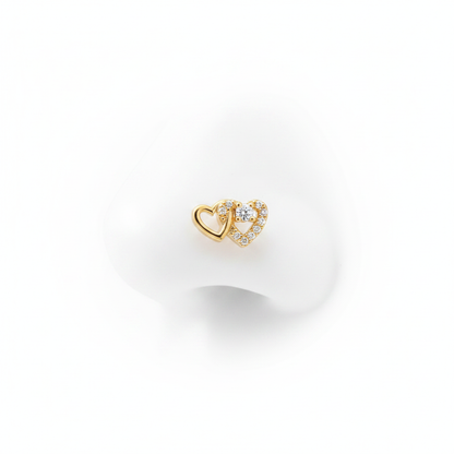 A luxury 18k gold-dipped nose stud featuring two interlocking hearts—one in polished gold and the other pavé-set with brilliant crystals—crafted from tarnish-resistant titanium steel for a minimalist editorial look.