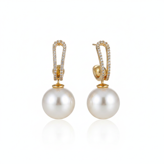 Elegant 18k gold-dipped drop earrings featuring large, radiant pearls suspended from structural, crystal-pavé hoops, crafted from tarnish-resistant titanium steel for a sophisticated editorial aesthetic.