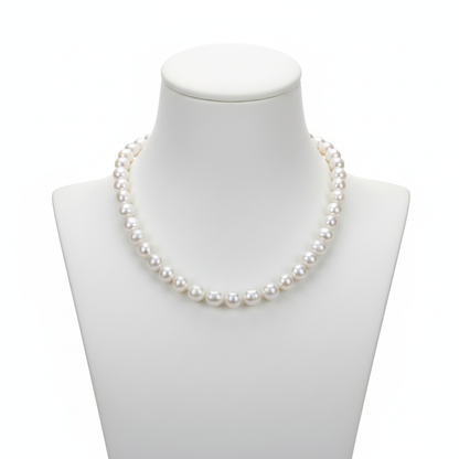 A classic strand of high-lustre, uniform white pearls displayed on a minimalist white bust, representing a foundational piece for a refined jewelry collection with a clean, editorial aesthetic.
