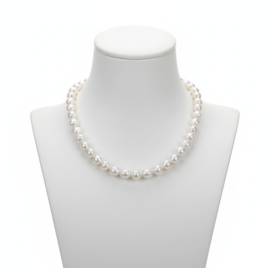 A classic strand of high-lustre, uniform white pearls displayed on a minimalist white bust, representing a foundational piece for a refined jewelry collection with a clean, editorial aesthetic.