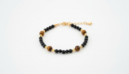 Beaded bracelet featuring polished black onyx beads and natural brown tiger’s eye stones with gold-tone spacers and an adjustable chain.