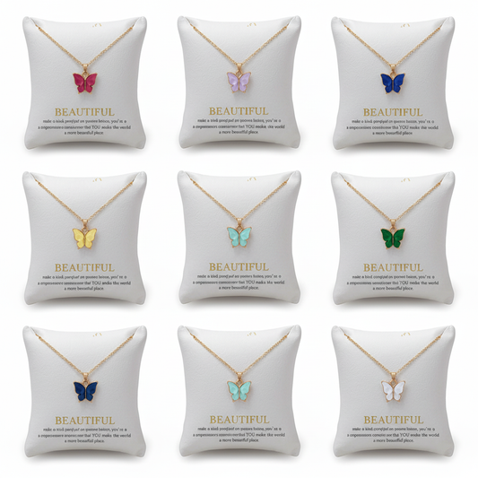 Multiple gold chain necklaces with colorful butterfly charms displayed on elegant white padded jewelry pillows