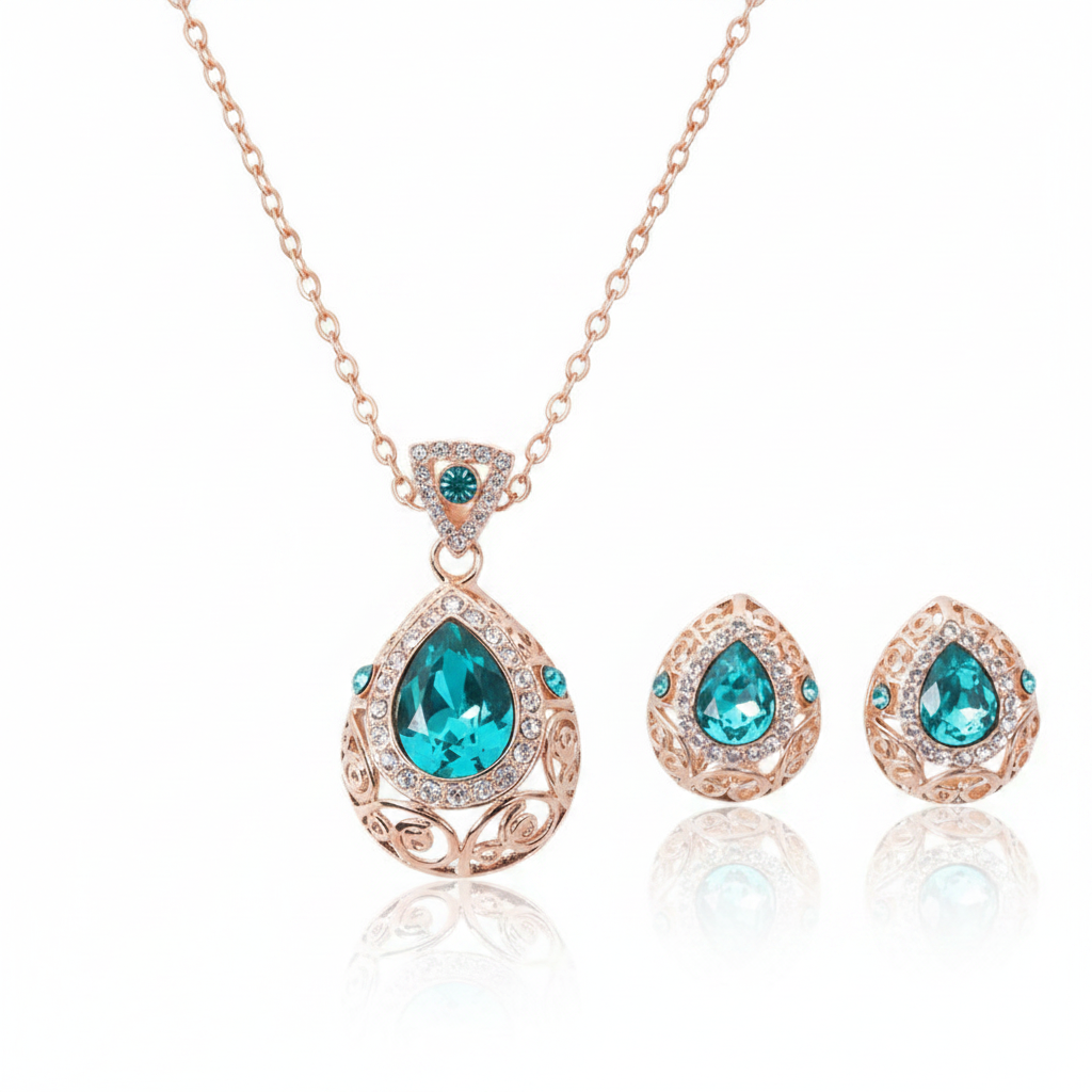 An ornate rose gold jewelry set featuring a teardrop-shaped teal crystal pendant necklace and matching stud earrings with intricate filigree detailing and pavé accents.